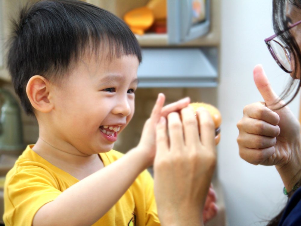 A child high-fives his teacher during a role-play activity