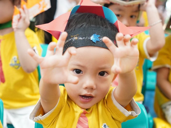 A child in a handmade hat reaching towards the camera